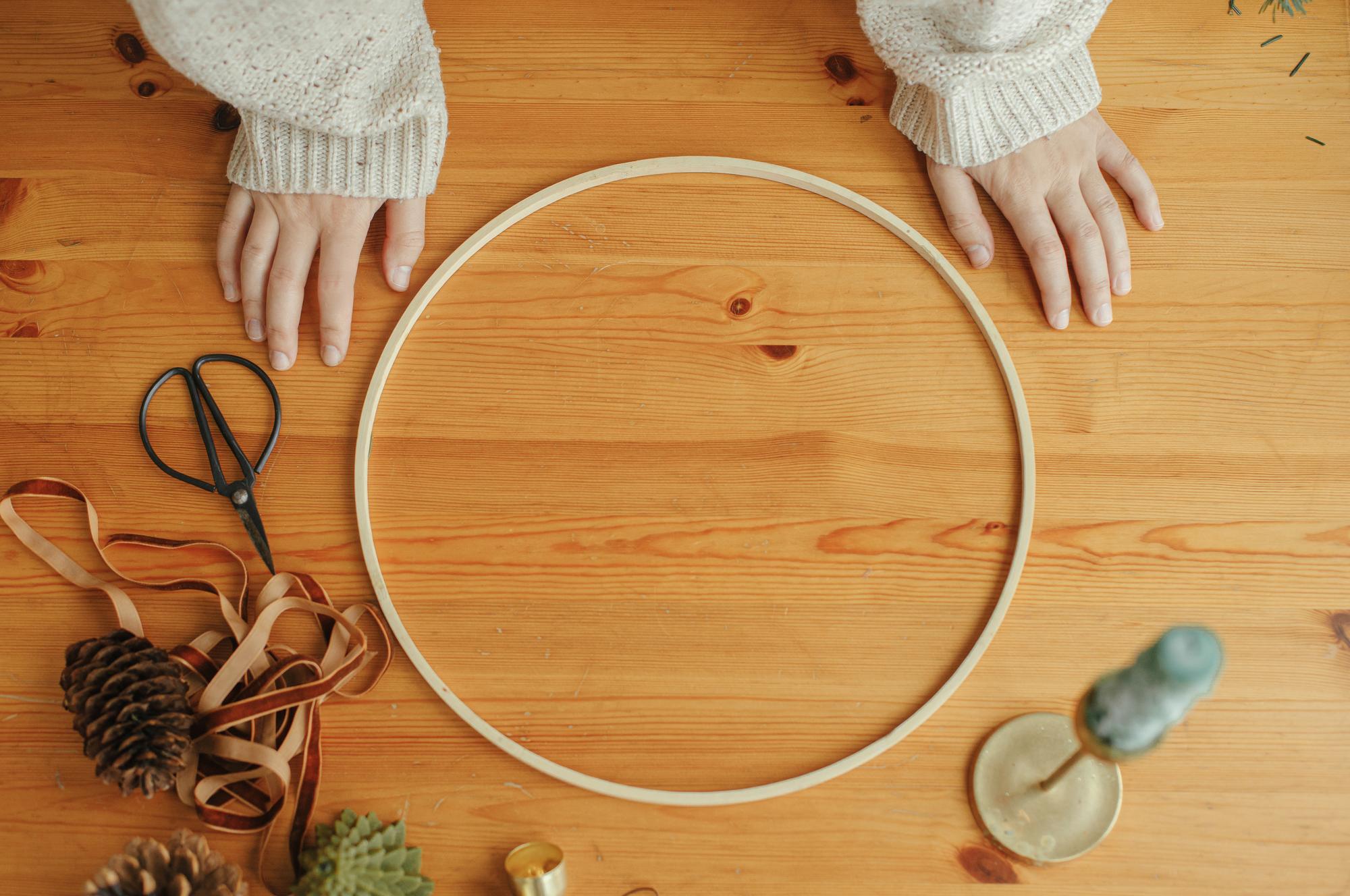 studio hands arranging threads and hoops on a wooden table