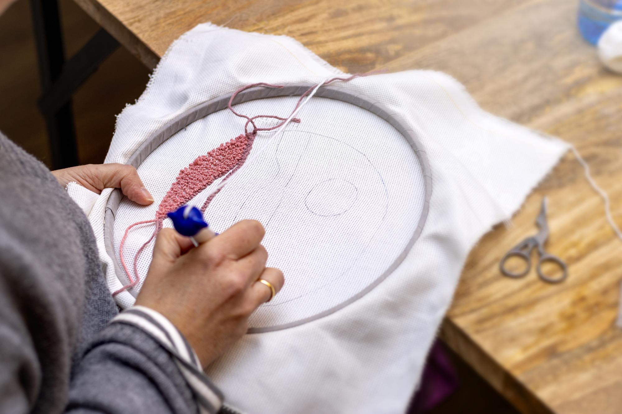 artist stitching a sample on hoop
